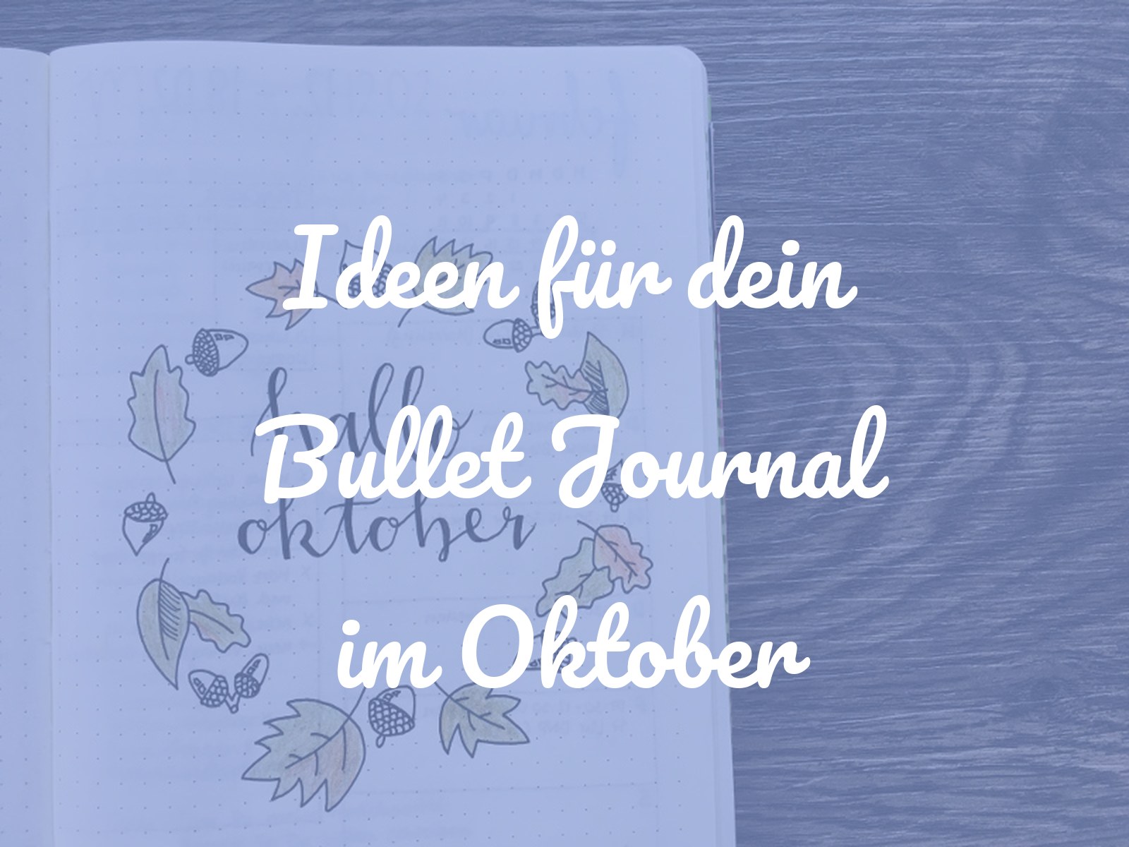 Bullet-Journal-Deckblatt mit dem Schriftzug hallo oktober, umrahmt von einem Kranz aus bunt kolorierten Herbstblättern und Eicheln
